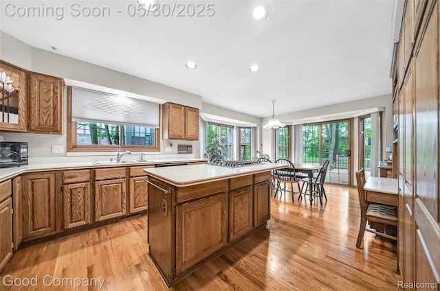 38836 Westchester Ln, Northville, MI 48167 - kitchen with brown cabinets, a sink, light wood-style flooring, black microwave, and a center island