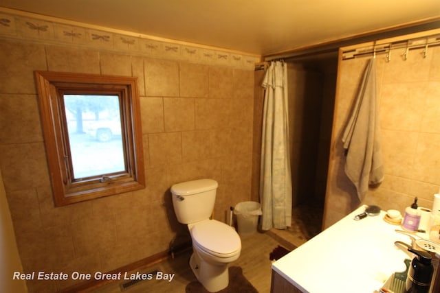 4141 Sagatoo Rd, Standish, MI 48658 - full bathroom with tile walls, a shower with shower curtain, toilet, and wood finished floors
