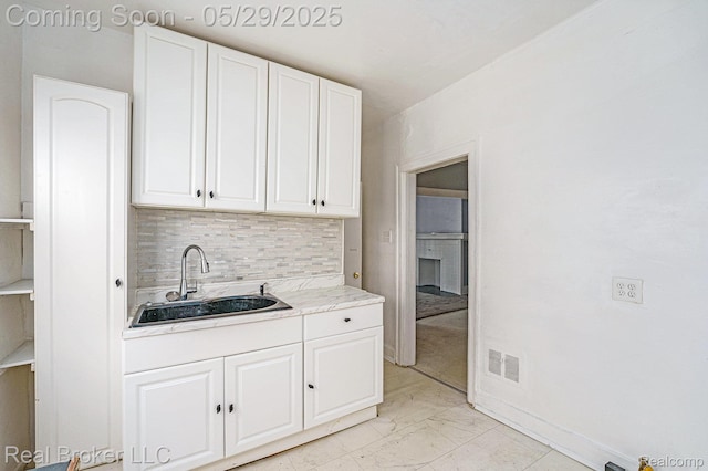9419 Ravenswood St, Detroit, MI 48204 - kitchen featuring a sink, white cabinets, light countertops, light marble finish flooring, and decorative backsplash