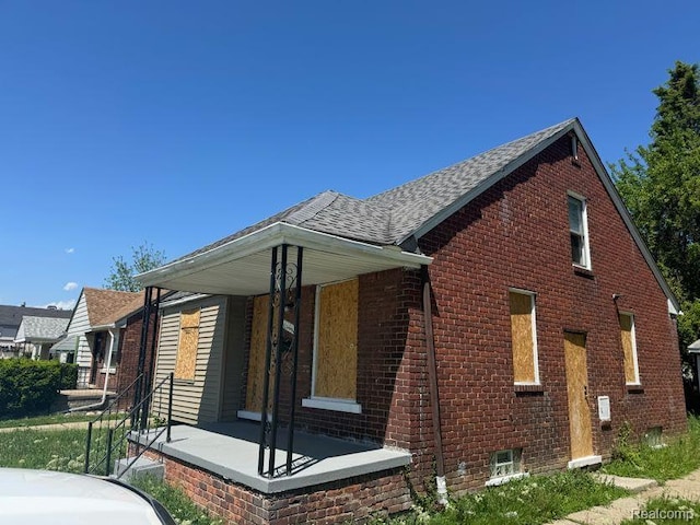 6106 Cadieux Rd, Detroit, MI 48224 - view of side of home featuring a porch, brick siding, and roof with shingles