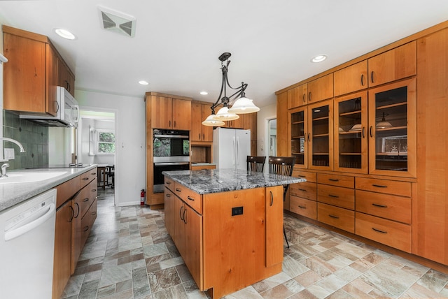 10827 N 12th St, Plainwell, MI 49080 - kitchen with white appliances, a kitchen island, brown cabinets, recessed lighting, and a sink