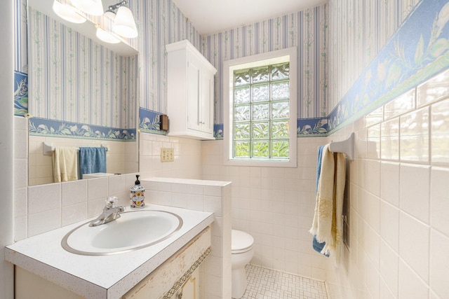 10827 N 12th St, Plainwell, MI 49080 - half bathroom with wallpapered walls, tile walls, toilet, wainscoting, and vanity