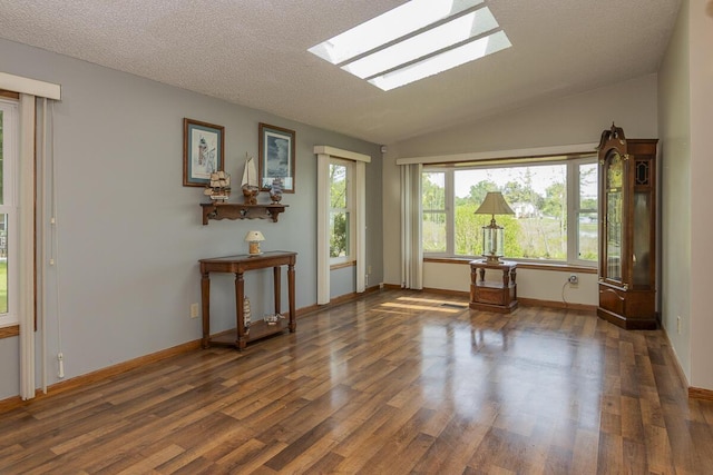 10303 Walnut Dr, Three Rivers, MI 49093 - empty room featuring a skylight, wood finished floors, vaulted ceiling, a textured ceiling, and baseboards