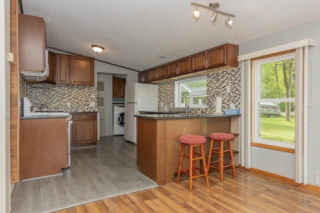 10303 Walnut Dr, Three Rivers, MI 49093 - kitchen featuring washer / dryer, a peninsula, dark countertops, tasteful backsplash, and a textured ceiling