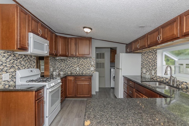 10303 Walnut Dr, Three Rivers, MI 49093 - kitchen with white appliances, a sink, washer / clothes dryer, light wood-style flooring, and dark stone counters