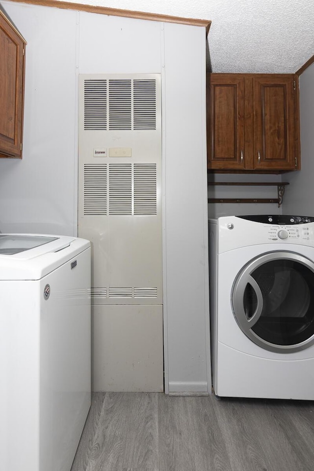 10303 Walnut Dr, Three Rivers, MI 49093 - laundry room with cabinet space, light wood-style flooring, and a heating unit