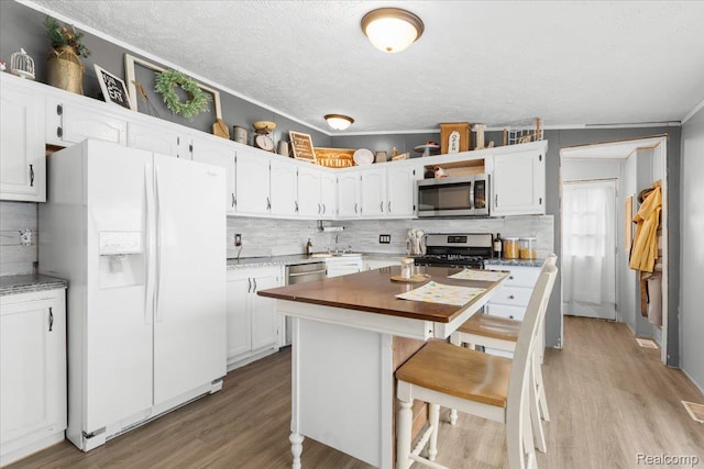 351 N Squirrel Rd, Auburn Hills, MI 48326 - kitchen featuring appliances with stainless steel finishes, a textured ceiling, decorative backsplash, light wood-style flooring, and white cabinetry