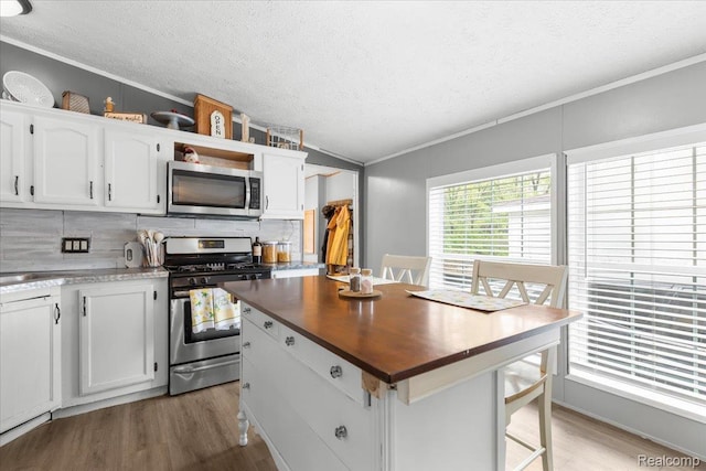 351 N Squirrel Rd, Auburn Hills, MI 48326 - kitchen featuring stainless steel appliances, crown molding, a textured ceiling, vaulted ceiling, and light wood-type flooring