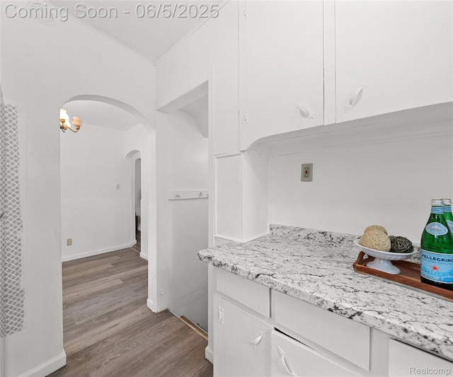 31777 Hennepin St, Garden City, MI 48135 - kitchen featuring arched walkways, white cabinetry, wood finished floors, ornamental molding, and light stone countertops