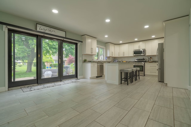 14607 Stratford, Shelby Twp, MI 48315 - kitchen with appliances with stainless steel finishes, tasteful backsplash, a kitchen bar, white cabinetry, and a center island