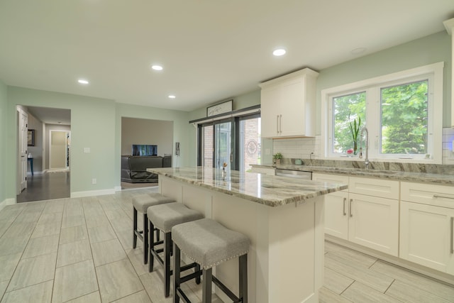 14607 Stratford, Shelby Twp, MI 48315 - kitchen featuring a sink, a kitchen island, light stone countertops, a breakfast bar area, and backsplash