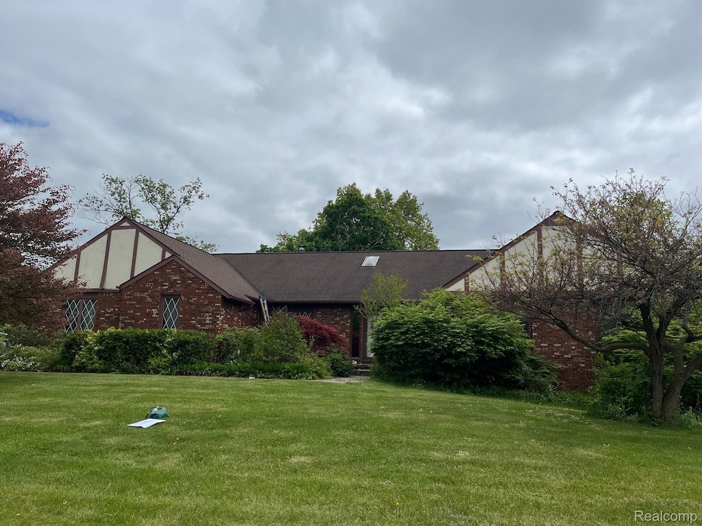 2149 Russet Dr, Troy, MI 48098 - tudor-style house featuring a front yard and brick siding