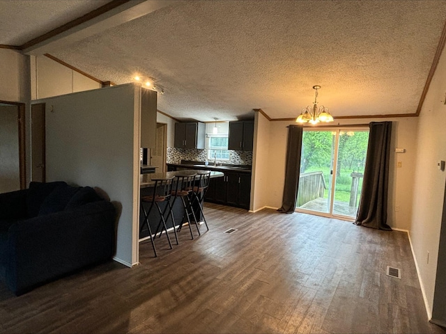 815 Hyatt St, Eaton Rapids, MI 48827 - kitchen with dark wood-style flooring, a chandelier, backsplash, dark countertops, and open floor plan