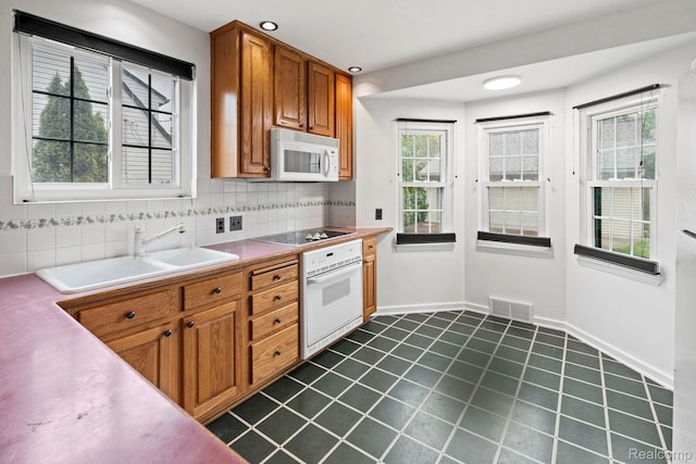99 Wenonah Dr, Pontiac, MI 48341 - kitchen featuring white appliances, a sink, brown cabinetry, decorative backsplash, and plenty of natural light