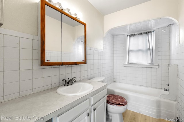 8492 Meadow Ave, Warren, MI 48089 - full bathroom featuring tile walls, toilet, vanity, wood finished floors, and tub / shower combination
