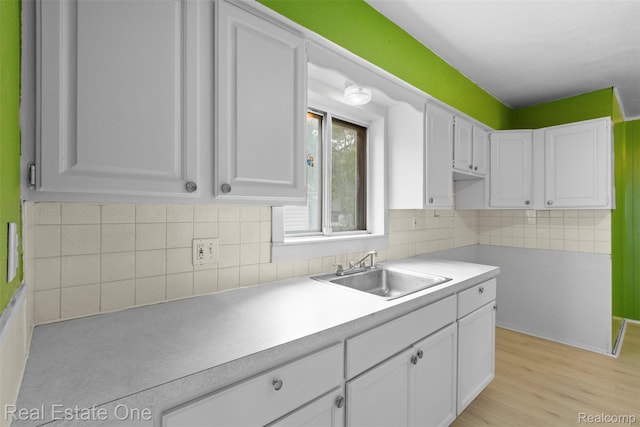 8492 Meadow Ave, Warren, MI 48089 - kitchen with a sink, white cabinetry, light countertops, and backsplash