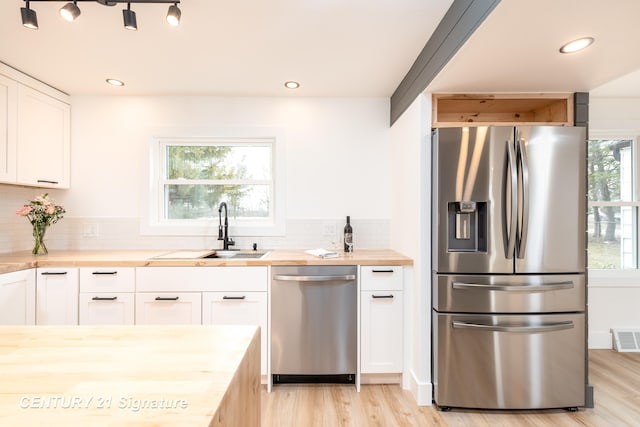 2705 Mccarty Rd, Saginaw, MI 48603 - kitchen with appliances with stainless steel finishes, wood counters, a sink, light wood-style flooring, and decorative backsplash
