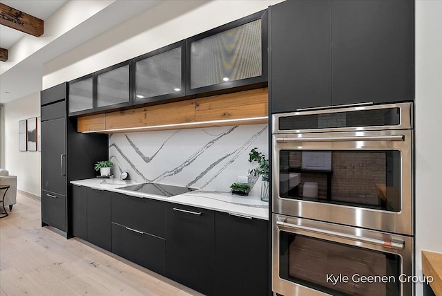 52 E 8th St Ste 210, Holland, MI 49423 - kitchen featuring stainless steel double oven, dark cabinets, light wood-style floors, backsplash, and light countertops