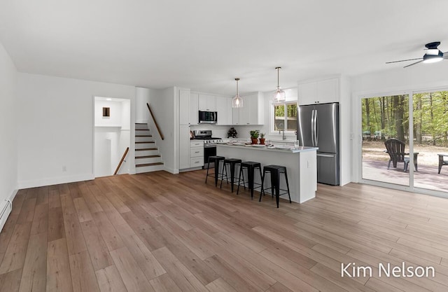 5203 Nestrom Rd, Whitehall, MI 49461 - kitchen featuring appliances with stainless steel finishes, a breakfast bar, a kitchen island, white cabinets, and light wood-style flooring
