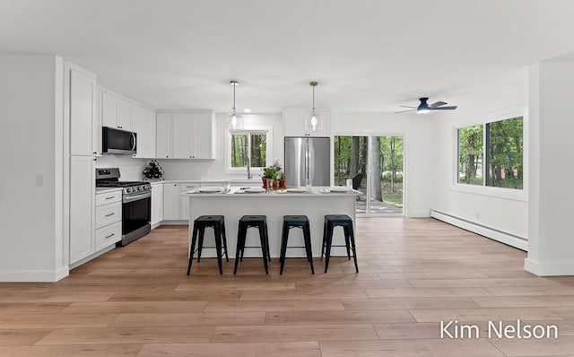 5203 Nestrom Rd, Whitehall, MI 49461 - kitchen featuring stainless steel appliances, a baseboard radiator, plenty of natural light, and a kitchen bar