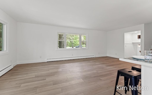 5203 Nestrom Rd, Whitehall, MI 49461 - unfurnished living room with a baseboard heating unit, healthy amount of natural light, and light wood-type flooring