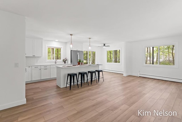 5203 Nestrom Rd, Whitehall, MI 49461 - kitchen with stainless steel fridge, baseboard heating, a baseboard radiator, and white cabinetry