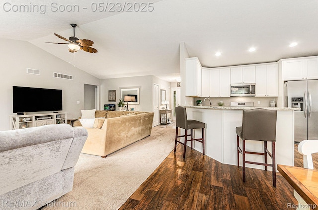 5956 Kerri Ln, Howell, MI 48855 - kitchen with stainless steel appliances, a breakfast bar, ceiling fan, white cabinets, and vaulted ceiling