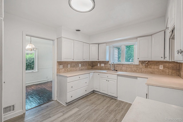 2952 Clement St, Flint, MI 48504 - kitchen with a sink, light wood finished floors, white cabinets, and light countertops