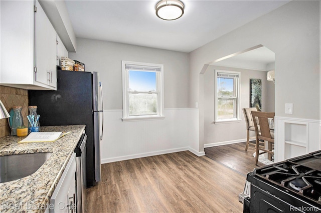 14620 Trenton Rd, Southgate, MI 48195 - kitchen featuring arched walkways, healthy amount of natural light, a sink, white cabinetry, and wainscoting