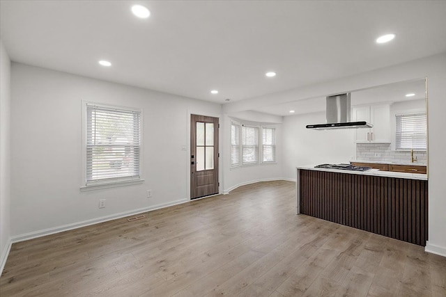 1437 Pearson St, Ferndale, MI 48220 - kitchen with wall chimney exhaust hood, white cabinets, stainless steel gas cooktop, light wood finished floors, and light countertops