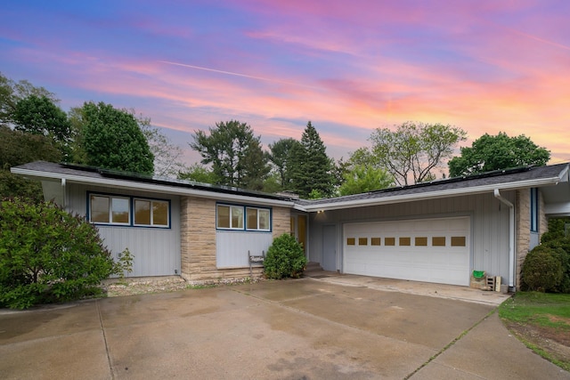 812 W Center, Alma, MI 48880 - view of front of property featuring an attached garage, concrete driveway, solar panels, and board and batten siding