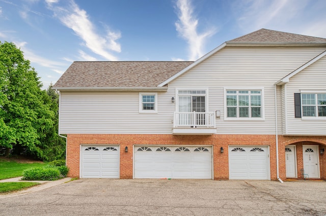 760 Olde English Cir, Howell, MI 48855 - rear view of property featuring asphalt driveway, brick siding, an attached garage, and roof with shingles