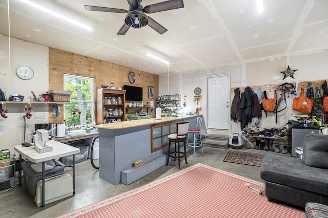 3921 Wildwood Ave, Bitely, MI 49309 - living room featuring concrete floors, ceiling fan, and wood walls