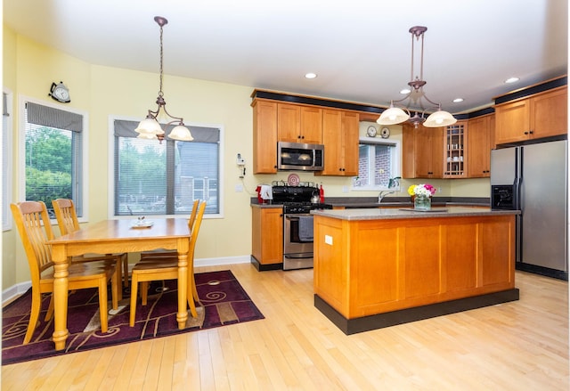 7009 Suncrest Dr, Saline, MI 48176 - kitchen featuring stainless steel appliances, light wood-style flooring, glass insert cabinets, a center island, and recessed lighting