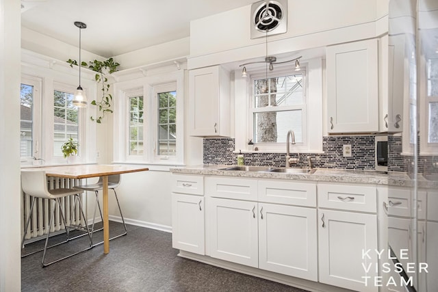 1058 Eastwood Ave SE, East Grand Rapids, MI 49506 - kitchen with a sink, baseboards, plenty of natural light, and white cabinets