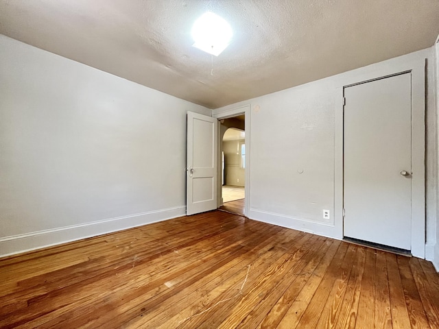 1837 Franklin St, Muskegon, MI 49441 - unfurnished bedroom with arched walkways, wood-type flooring, and baseboards