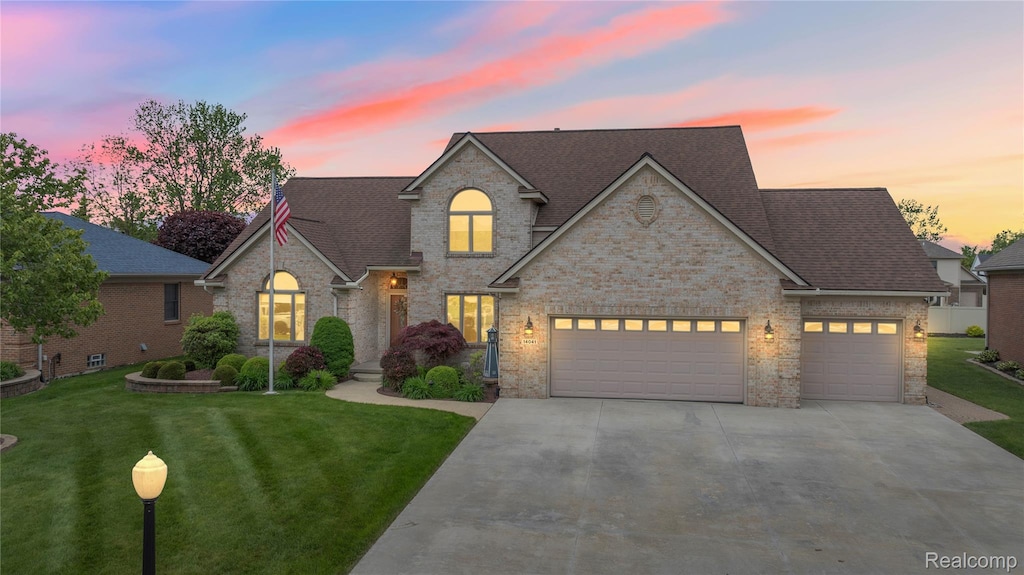 14041 Humbug Island Ct, Gibraltar, MI 48173 - view of front of home with driveway, a yard, a garage, brick siding, and roof with shingles