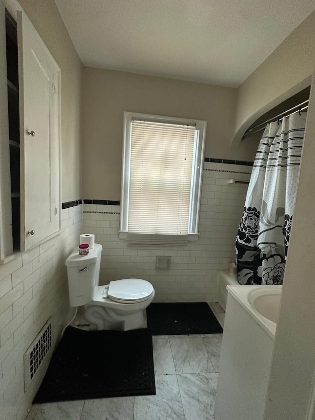 13639 Mecca St, Detroit, MI 48227 - bathroom featuring tile walls, toilet, wainscoting, curtained shower, and marble finish floors