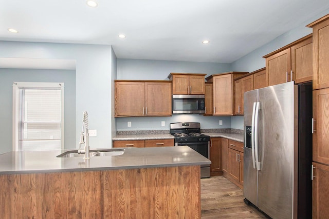 737 Bates St SE, Grand Rapids, MI 49503 - kitchen with stainless steel appliances, recessed lighting, light wood-style flooring, brown cabinetry, and an island with sink