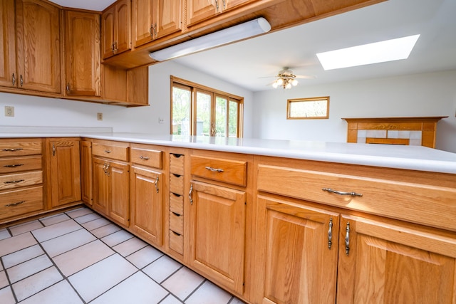 5142 Becht Rd, Coloma, MI 49038 - kitchen featuring a skylight, light countertops, light tile patterned floors, brown cabinetry, and a ceiling fan