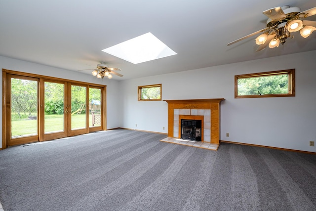 5142 Becht Rd, Coloma, MI 49038 - unfurnished living room featuring a ceiling fan, a tiled fireplace, baseboards, a skylight, and carpet floors