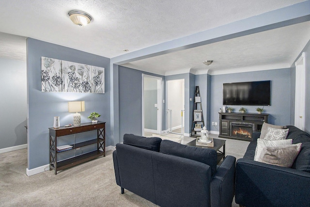 1912 E Centre Ave, Portage, MI 49002 - living room featuring light colored carpet, baseboards, a warm lit fireplace, and a textured ceiling