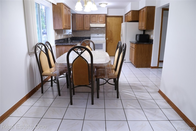 18675 Webster Ave, Southfield, MI 48076 - kitchen with white appliances, under cabinet range hood, a sink, baseboards, and a chandelier
