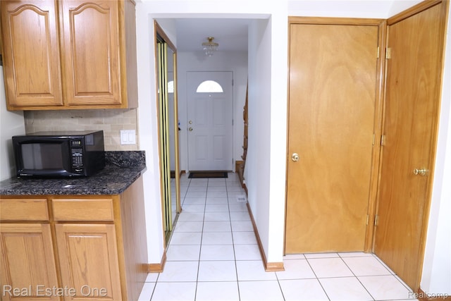 18675 Webster Ave, Southfield, MI 48076 - kitchen featuring black microwave, light tile patterned floors, dark stone counters, and baseboards