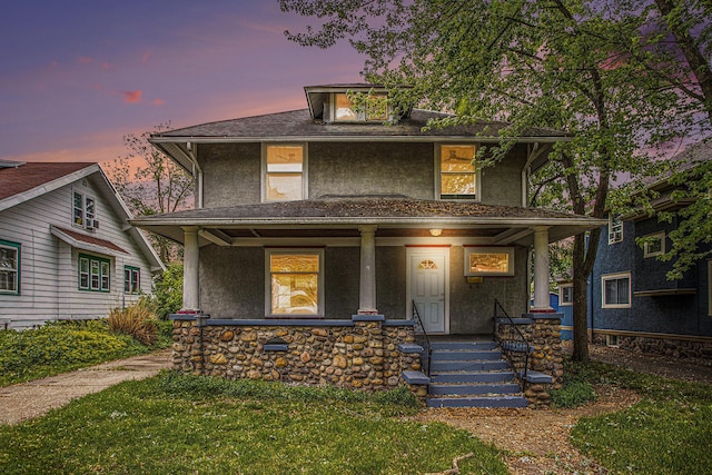 176 N Union St, Battle Creek, MI 49017 - american foursquare style home featuring covered porch, stucco siding, a front yard, and stone siding