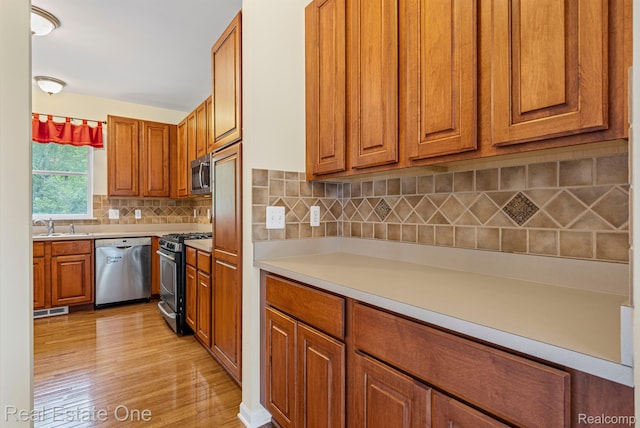 29329 Whistler Dr, Novi, MI 48377 - kitchen featuring appliances with stainless steel finishes, brown cabinetry, light wood-style flooring, and a sink
