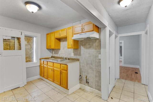 2174 Springle St, Detroit, MI 48215 - kitchen featuring under cabinet range hood, a textured ceiling, light tile patterned flooring, light countertops, and a sink