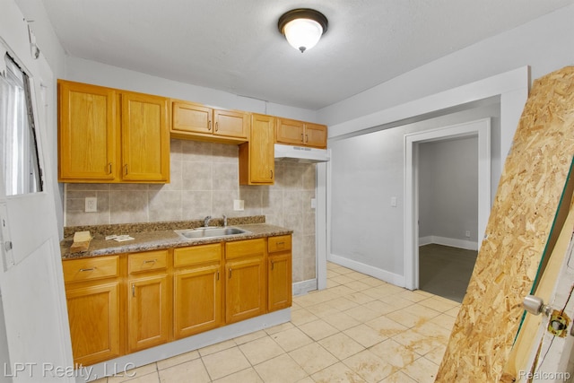 2174 Springle St, Detroit, MI 48215 - kitchen with a sink, under cabinet range hood, light tile patterned floors, stone countertops, and baseboards