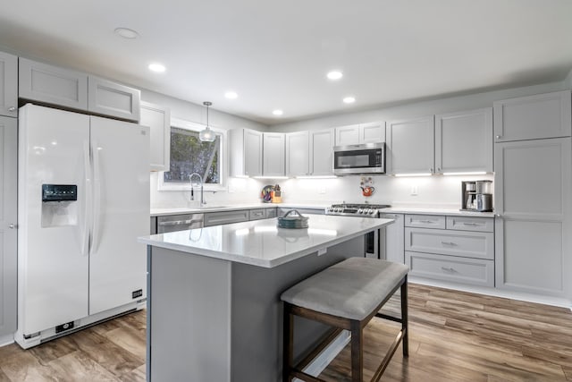 7256 Highland Dr, Beulah, MI 49617 - kitchen with stainless steel appliances, a kitchen breakfast bar, wood finished floors, a kitchen island, and recessed lighting