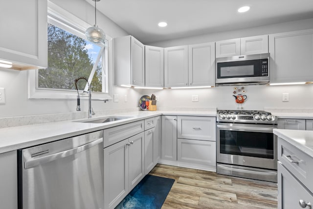 7256 Highland Dr, Beulah, MI 49617 - kitchen featuring appliances with stainless steel finishes, a sink, light countertops, recessed lighting, and light wood-type flooring